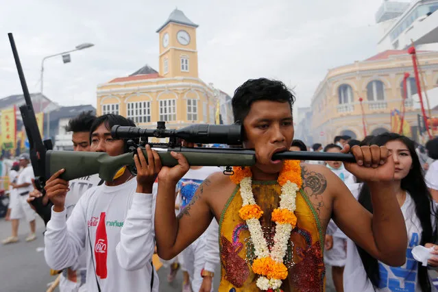 A devotee of the Chinese Bang Neow shrine with a gun barrel pierced through his cheek takes part in a procession celebrating the annual vegetarian festival in Phuket, Thailand October 6, 2016. (Photo by Jorge Silva/Reuters)