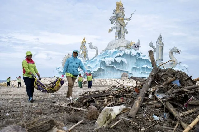 Workers clean debris and plastic waste at a beach in Kuta, Bali, Indonesia, 02 February 2023. Most of the trash ends up in the sea every rainy season due to the island's lack of a centralized waste management system. (Photo by Made Nagi/EPA)