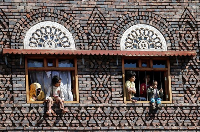 Children watch from the windows of their house as mourners pass during the funeral of Abdul Qader Helal, the mayor of Sanaa, the capital of Yemen, who was killed by an apparent Saudi-led air strike that ripped through a wake attended by some of the country's top political and security officials in Sanaa, October 10, 2016. (Photo by Khaled Abdullah/Reuters)