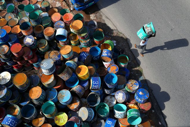 A man carries metal drums to Kaptai Lake on August 20, 2025 where fishers will use them to land their catch. (Photo by Syed Mahabubul Kader/ZUMA Press Wire/Rex Features/Shutterstock)