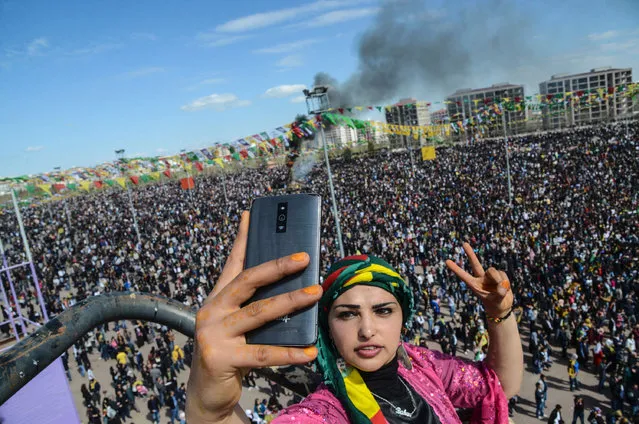 A woman takes a selfie picture with her mobile phone as Turkish Kurds gather during Newroz celebrations in Diyarbakir, on March 21, 2016. Nowruz, the Farsi-language word for “New Year”, is an ancient Persian festival, celebrated on the first day of spring, on March 21, in Central Asian republics, Iraq, Turkey, Afghanistan and Iran. (Photo by Ilyas Akengin/AFP Photo)