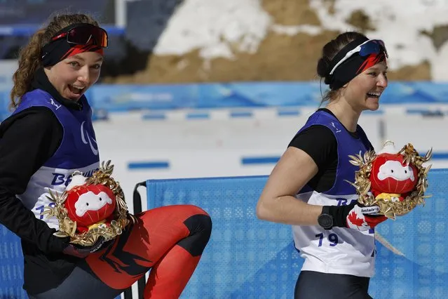 Natalie Wilkie of Canada celebrates with third placed Brittany Hudak of Canada during the flower ceremony for the Para Cross-Country Skiing, Women's Long Distance Classical Technique Standing at National Biathlon Centre in Zhangjiakou, China on March 7, 2022. (Photo by Issei Kato/Reuters)