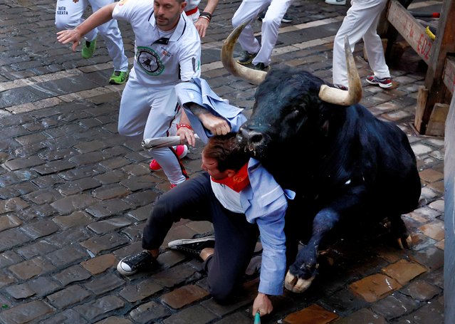 A runner falls in front of a bull, during the running of the bulls at the San Fermin festival in Pamplona, Spain on July 8, 2024. (Photo by Vincent West/Reuters)