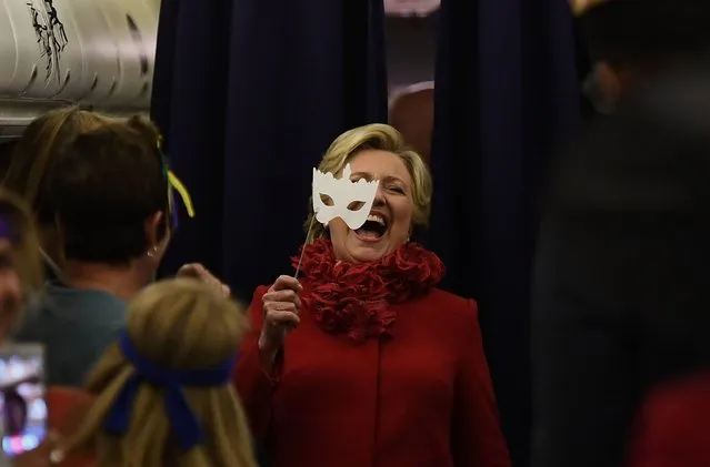 US Democratic presidential nominee Hillary Clinton smiles holding a mask onboard her campaign plane Erlanger, Kentucky, on October 31, 2016. Clinton campaigned Monday for a third straight day without close aide Huma Abedin, linked by media to the renewed FBI probe into the former secretary of state's use of a private email server. The Federal Bureau of Investigation jolted the US presidential race Friday with the announcement it was reviewing a new batch of emails that appeared to be pertinent to the Clinton case. (Photo by Jewel Samad/AFP Photo)