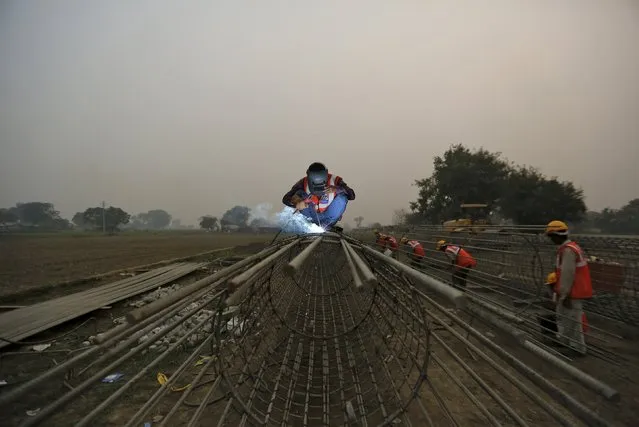 Labourers work at the construction site of a bridge being built for metro rail in New Delhi, India, November 30, 2015. (Photo by Anindito Mukherjee/Reuters)