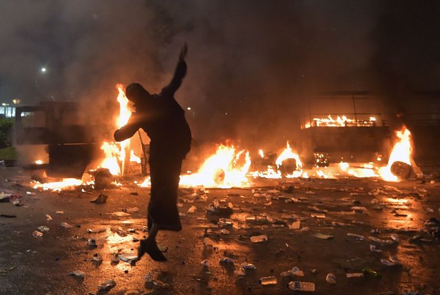 An Indonesian protester throws a rock next to burning cars outside the presidential palace during clashes after a rally against governor Basuki Tjahaja Purnama, a Christian accused of insulting Islam, in Jakarta on November 4, 2016. A massive demonstration by tens of thousands of Indonesian Muslims against Jakarta's governor turned ugly as hardliners burned police cars and clashed with officers, who responded with tear gas and water cannons. (Photo by Adek Berry/AFP Photo)