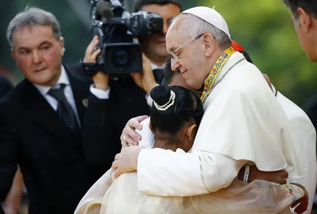 Pope Francis embraces a boy and a girl during a meeting with young people at Manila university, January 18, 2015. (Photo by Stefano Rellandini/Reuters)