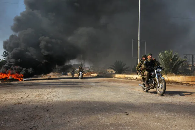 Rebel fighters drive their motorcycles under the smoke of burning tyres, western Aleppo city, Syria November 3, 2016. (Photo by Ammar Abdullah/Reuters)