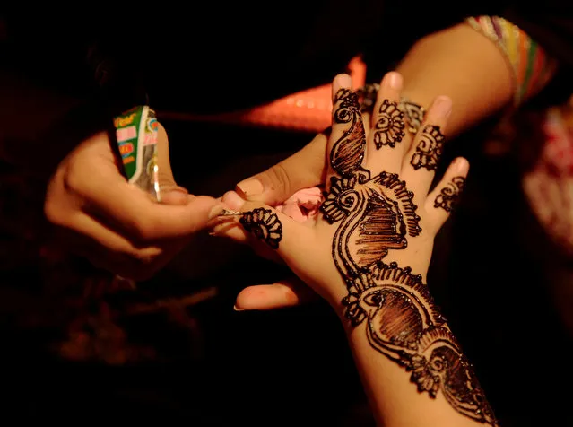 A girl applies mehndi (a henna tattoo) on the hand of a customer at a stall ahead of Eid al-Fitr, which marks the end of the holy month of Ramadan, in Islamabad, Pakistan June 13, 2018. (Photo by Faisal Mahmood/Reuters)