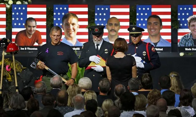 An honor guard presents families with American flags during a memorial service at Tim's Toyota Center in Prescott Valley, Arizona, on July 9, 2013. 19 firefighters of the Granite Mountain Hotshots crew died battling a fast-moving wildfire on June 30. (Photo by David Kadlubowskil/Getty Images)