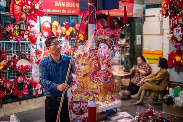 A vendor prepares his Lunar New Year decoration items at the Spring Festival Fair in the Old Quarter on January 14, 2023 in Hanoi, Vietnam. The Lunar New Year also known as the Spring Festival or Chinese New Year, which is based on the Lunisolar Chinese calendar, falls on January 20 this year and marks the Year of the Cat in Vietnam or the Year of the Rabbit in China, Korea, and other East and Southeast Asian countries. (Photo by Linh Pham/Getty Images)