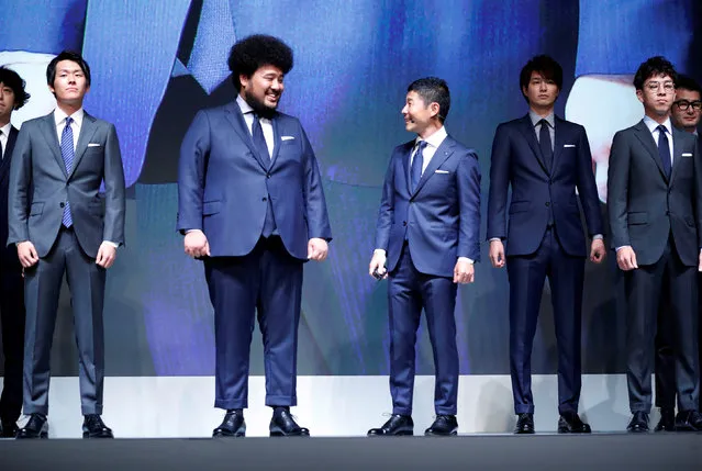 Yusaku Maezawa (3rd R), the chief executive of Zozo, which operates Japan's popular fashion shopping site Zozotown and is officially called Start Today Co, looks at his employee who wears a made-to-measure suit using a skintight bodysuit which helps customers upload their measurements online at an event launching the debut of its formal apparel items, in Tokyo, Japan, July 3, 2018. (Photo by Kim Kyung-Hoon/Reuters)