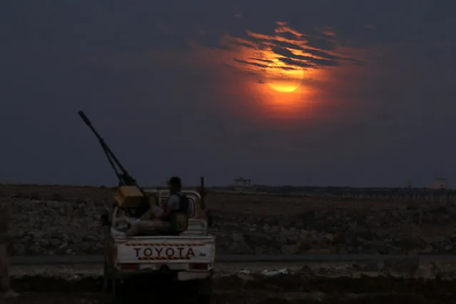 A Free Syrian army fighter sits on a pick-up truck mounted with a weapon, as the supermoon partly covered by clouds is seen in the background, in the west of the rebel-held town of Dael, in Deraa Governorate, Syria  November 14, 2016. (Photo by Alaa Al-Faqir/Reuters)