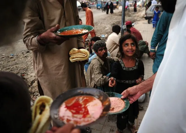 Pakistani residents eat food given out by a charity outside a restaurant in Karachi on April 8, 2016. Nearly 60 million people live below the poverty line in Pakistan, making almost a third of the country poor under a new formula adopted by the government to measure poverty. The report, from Pakistan's Planning Commission, estimates that adults in up to 7.6 million households are earning less than 3,030 rupees per month ($30), raising poverty levels to 29.5 percent from nine percent under former estimates. (Photo by Asif Hassan/AFP Photo)