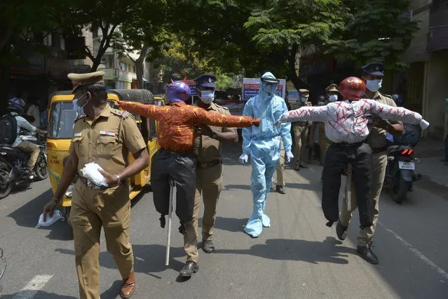 Policemen hold effigys of demons representing the Covid-19 Coronavirus during an awareness campaign along a street in Chennai on April 9, 2021 as India surged past 13 million coronavirus cases. (Photo by Arun Sankar/AFP Photo)