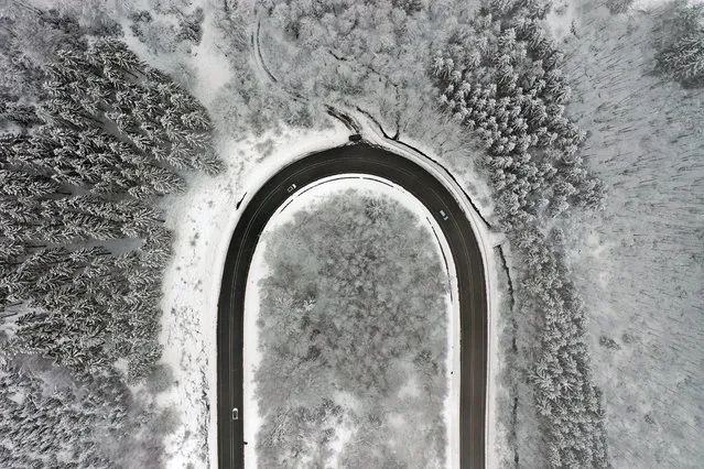 An aerial view shows cars driving on a street in a snow-covered landscape at the Nordhelle mountain near Meinerzhagen, western Germany, on January 7, 2021. The winter weather in the upper parts of Germany attracts many visitors. (Photo by Ina Fassbender/AFP Photo)