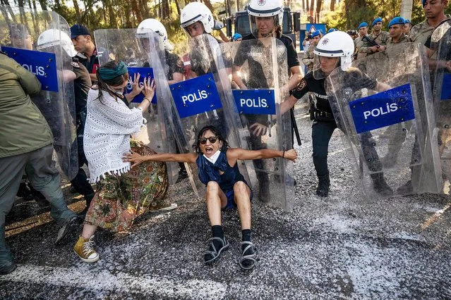 A protestor resists against Turkish police during clashes in Ikizkoy, in the Milas district of the Province of Mugla, on July 29, 2023. Local residents and environmental activists demonstrate for the fifth day against the deforestation project of the 750-decare century-old pine forest, intended to expand a lignite field in the forests of Akbelen in Ikizkoy, leading to clashes with Turkish Gendarmerie. (Photo by Bulent Kilic/AFP Photo)