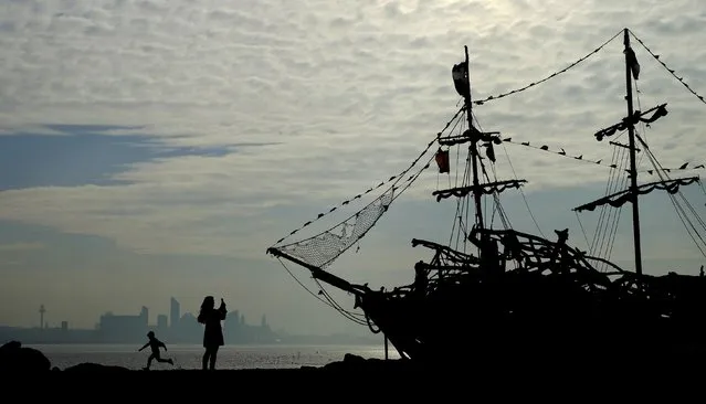 People play in front of a driftwood pirate ship on New Brighton beach near Wallasey in Britain October 25, 2016. (Photo by Phil Noble/Reuters)
