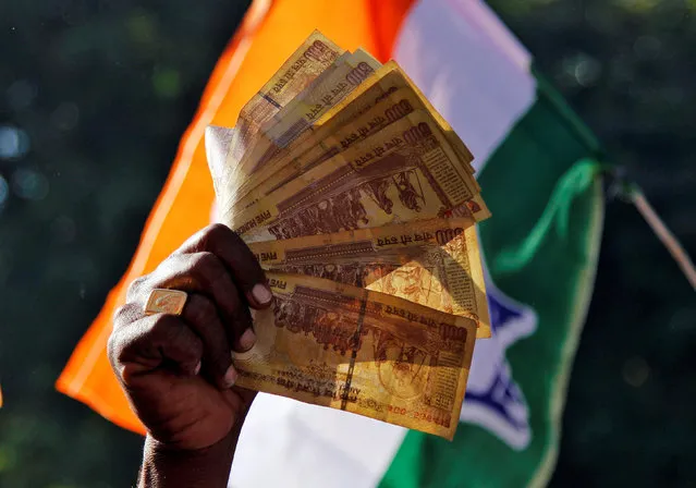 A man displays 500 Indian rupee notes during a rally organised by India’s main opposition Congress party against the government's decision to withdraw 500 and 1000 Indian rupee banknotes from circulation, in Ajmer, India, November 24, 2016. (Photo by Himanshu Sharma/Reuters)