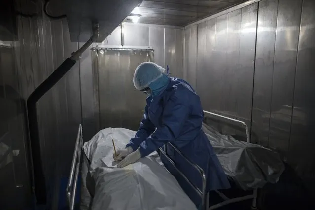 A healthcare worker fills out paper work for a patient who died from COVID-19, in a morgue at the Samaritana Hospital in Bogota, Colombia, Thursday, June 3, 2021. (Photo by Ivan Valencia/AP Photo)