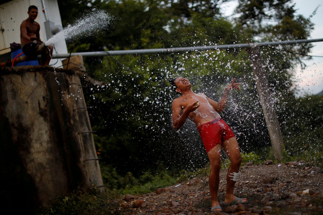 A migrant, part of a caravan of thousands traveling from Central America en route to the United States, takes a shower in Santiago Niltepec, Mexico, October 29, 2018. (Photo by Ueslei Marcelino/Reuters)