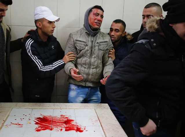 A Palestinian mourner reacts after spreading on his face the blood of Ahmad al-Kharoubi, 19, who was shot and killed during clashes with Israeli soldiers on December 22, 2016, before his funeral in the West Bank city of Ramallah. The Palestinian man was killed during clashes with Israeli soldiers overnight as they arrived to demolish the home of the alleged perpetrator of a deadly attack on Israelis, the army said. (Photo by Abbas Momani/AFP Photo)