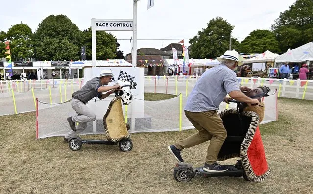 Two men race on “electric horses” in the funfair area at the Royal International Horse Show in West Sussex, England on July 28, 2022. (Photo by Garry Bowden/Rex Features/Shutterstock)