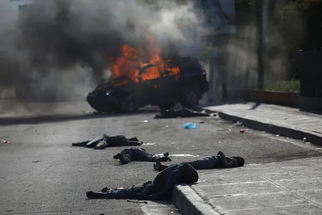Dead bodies lie on a road next to the car that crashed into them on a street of Port-au-Prince, Haiti, November 21, 2018. The car was set on fire by onlookers after the accident. (Photo by Andres Martinez Casares/Reuters)