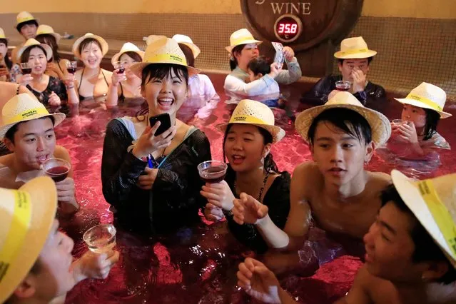 People raise their glasses filled with 2018 Beaujolais Nouveau wine as they bathe in a colored hot water “wine bath” at Hakone Kowakien Yunessun hot spring resort in Hakone, west of Tokyo, Japan, 15 November 2018, on the day of the Beaujolais Nouveau official release. Japan is a major market for the Beaujolais Nouveau and according to local media reports, about 5.3 million bottles of the wine will be imported in Japan by the end of the year. (Photo by Franck Robichon/EPA/EFE)