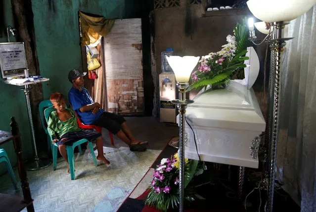 The father and younger brother of Jonel Segovia mourn near his coffin after Jonel was shot dead by suspected vigilantes at a house storing illegal narcotics, police said on Thursday, in Caloocan city, Metro Manila, in the Philippines December 29, 2016. (Photo by Erik De Castro/Reuters)