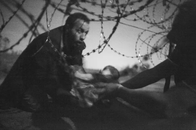 “Hope for a New Life”. Spot News, first prize singles. Warren Richardson, Australia. Location: Röszke, Hungary. A man passes a baby through the fence at the Hungarian-Serbian border in Röszke, Hungary, 28 August 2015. (Photo by Warren Richardson/World Press Photo Contest)