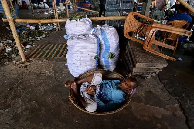 A man takes a nap on his basket at a wholesale market in Dhaka on November 6, 2023. (Photo by Munir Uz Zaman/AFP Photo)