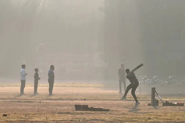Youths play cricket in a ground amid smoggy conditions in Lahore on November 14, 2023. (Photo by Arif Ali/AFP Photo)