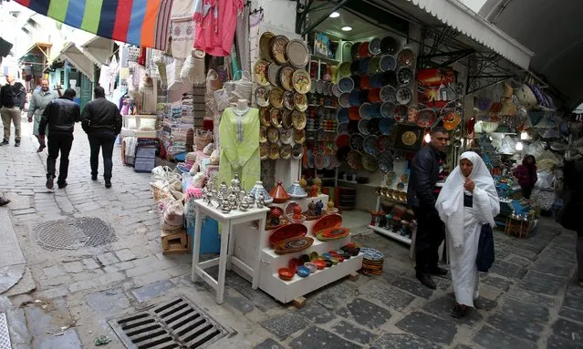 Tunisians walk near at a souvenir shop in the medina, the old city of Tunis, Tunisia, February 16, 2016. (Photo by Zoubeir Souissi/Reuters)