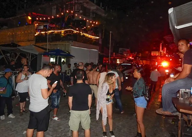 People remain in the street outside the Blue Parrot nightclub in Playa del Carmen, Quintana Ro state, Mexico where 5 people were killed, three of them foreigners, during a music festival on January 16, 2017. (Photo by Victor Vargas/AFP Photo)