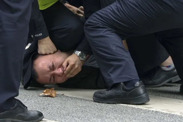 Policemen pin down and arrest a protester during a protest on a street in Shanghai, China on Sunday, November 27, 2022. Authorities eased anti-virus rules in scattered areas but affirmed China's severe “zero- COVID” strategy Monday after crowds demanded President Xi Jinping resign during protests against controls that confine millions of people to their homes. (Photo by AP Photo/Stringer)