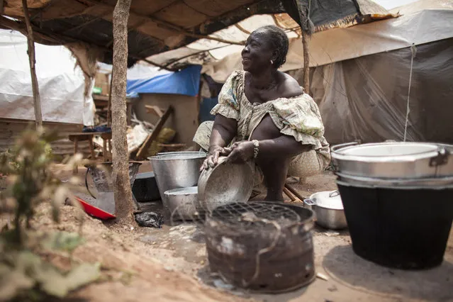 Marie Valentine, head of the women's community in M'Poko Internally Displace Persons camp washes dishes outside her tent in Bangui, Central African Republic on Tuesday, February 16, 2016. Due to the lack of food aid into the camp, many IDPs have grown their own food in private gardens to survive. But due to the lack of rain in recent months, many gardens are failing leaving the IDPs desperate for food once again. (Photo by Jane Hahn/The Washington Post)