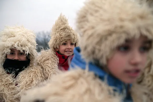 Bosnian Serb children warm themselves wrapped in a traditional outfit made of wool while riding on a horse-drawn carriage in the village of Glamocani, near Banja Luka, Bosnia, on Sunday, January 6, 2019. Like many other Orthodox Christians around the world, Serbs observe holidays according to the Julian calendar instead of the Gregorian calendar adopted during the 16th century, they celebrate Christmas on Jan. 7 instead of Dec. 25. (Photo by Amel Emric/AP Photo)