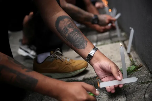 A fan with a tattoo depicting Brazilian football legend Pele places a candle during a vigil in front of the Albert Einstein Hospital where he is hospitalized in Sao Paulo, Brazil on December 4, 2022. (Photo by Carla Carniel/Reuters)