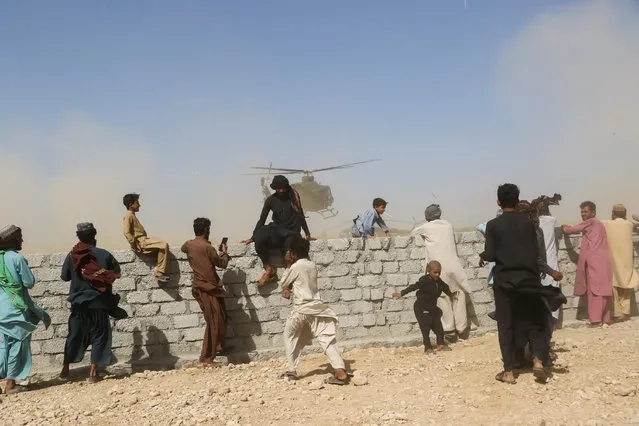 Residents gather as a rescue helicopter with medical supplies lands following an earthquake in Harnai, Balochistan, Pakistan, October 7, 2021. (Photo by Naseer Ahmed/Reuters)