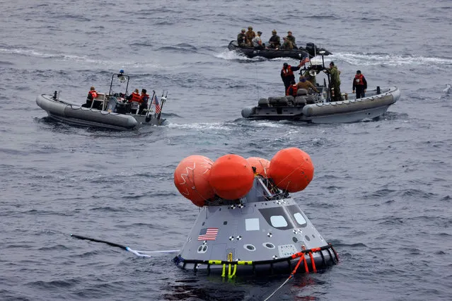The U.S. Navy team up with NASA’s Recovery Team as they work through the final certification run for recovering the Artemis I Orion space capsule by capturing a mock capsule into the bay of the USS John P. Murtha off the coast of California, U.S., November 4, 2021. (Photo by Mike Blake/Reuters)