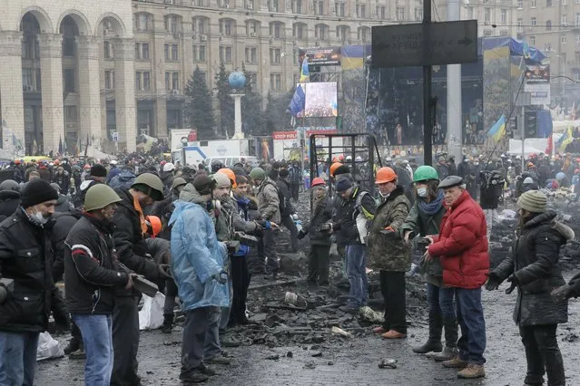 People pass stones to each other to use in attacks against police, during clashes with riot police in Kiev's Independence Square, the epicenter of the country's current unrest, Thursday, February 20, 2014. (Photo by Efrem Lukatsky/AP Photo)