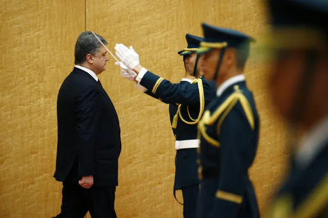 Ukrainian President Petro Poroshenko, left, inspects an honor guard before talks with Japan's Prime Minister Shinzo Abe at Abe's official residence in Tokyo, Wednesday, April 6, 2016. Poroshenko, who was in Japan to meet Abe and business leaders, defended himself earlier in the day in the massive leak of records on offshore accounts that has named political officials, business and celebrities from around the world. (Photo by Thomas Peter/Pool Photo via AP Photo)