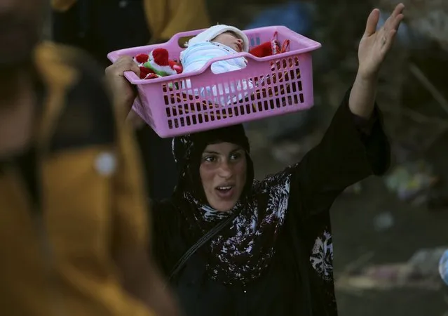 An Iraqi Sunni displaced woman, who fled the violence in the city of Ramadi carries her child on the outskirts of Baghdad, Iraq May 19, 2015. (Photo by Reuters/Stringer)