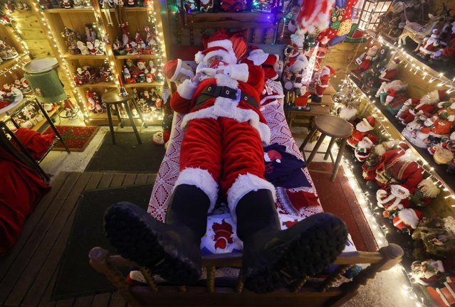 A man dressed as Santa Claus performs in the bedroom of a house that belongs to Serge Hennebel, nicknamed “Elf Serge”, and is transformed into a Christmas village adorned with thousands of lights, in Hamme-Mille, Belgium, December 17, 2021. (Photo by Yves Herman/Reuters)