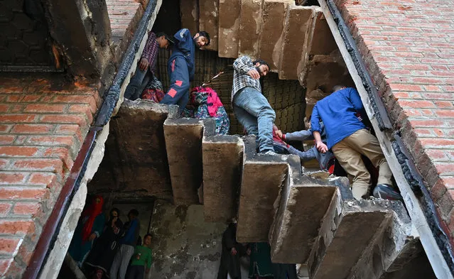 Kashmiri villagers look inside a damaged house following a gunfight between militants and Indian government forces at Panjran village in Pulwama, south of Srinagar, on June 7, 2019. Two low-ranking police deserters were among four rebels killed overnight in a firefight with government forces in Indian-administered Kashmir, the police and army said on June 7. (Photo by Tauseef Mustafa/AFP Photo)