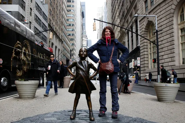 A woman poses next to a statue of a girl facing the Wall St. Bull, as part of a campaign by U.S. fund manager State Street to push companies to put women on their boards, in the financial district in New York, U.S., March 7, 2017. (Photo by Brendan McDermid/Reuters)