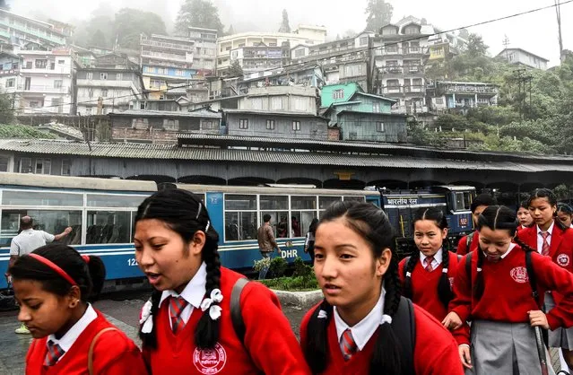 School children walk past a parked Darjeeling Himalayan Railway train, which runs on a 2 foot gauge railway and is a UNESCO World Heritage Site, at a station in Darjeeling, India, June 26, 2019. (Photo by Ranita Roy/Reuters)