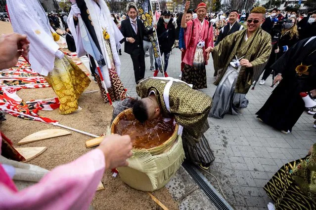 A 20-year-old man (C) puts his head in a sake barrel outside Todoroki Arena during a celebration ceremony to mark “Coming-of-Age Day” to honour people who turn 20 this year to signify adulthood, in Kawasaki, Kanagawa prefecture on January 10, 2022. (Photo by Behrouz Mehri/AFP Photo)