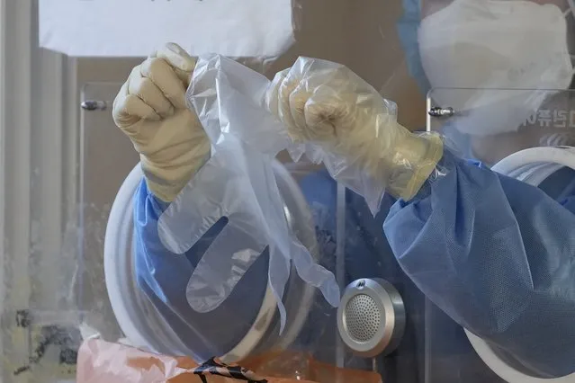 A medical worker in a booth wears plastic gloves at a temporary screening clinic for the coronavirus in downtown Seoul, South Korea, Monday, January 24, 2022. (Photo by Lee Jin-man/AP Photo/Pool)